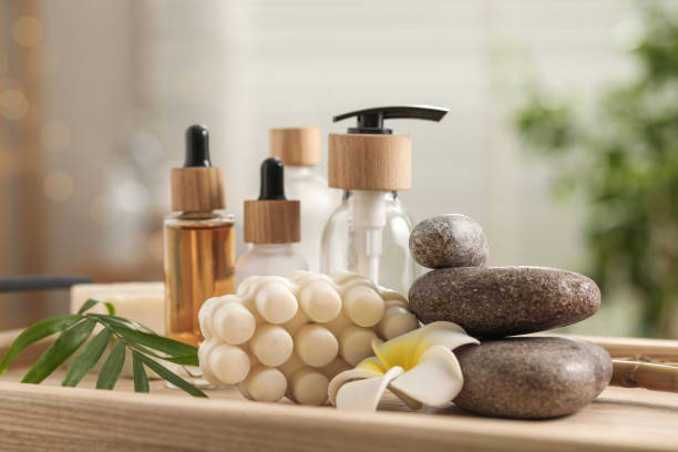 Composition with different spa products and plumeria flower on tray indoors