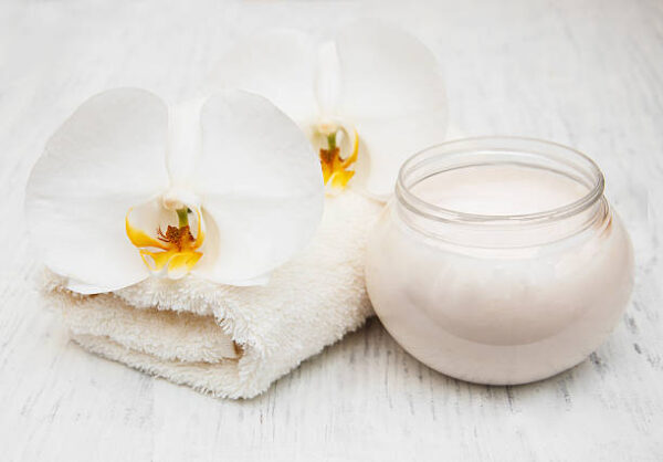 Orchids, cream and spa towels on a wooden background